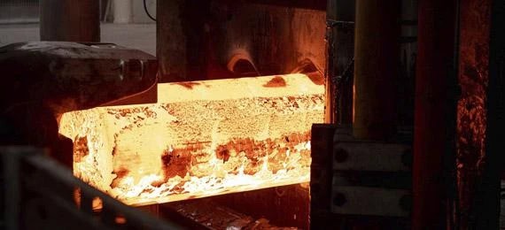 Hot steel being forged in a foundry with glowing metal.