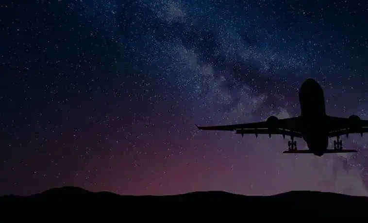 Night sky with stars and silhouette of airplane in flight.