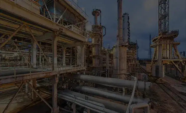 Industrial plant infrastructure with pipes and towers during evening hours.